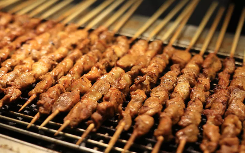 My photo of a pile of grilled arrosticini skewers on a plate, with a glass of red wine